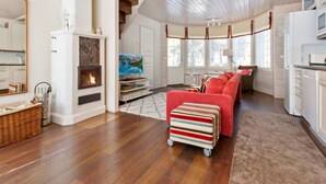Un salon spacieux avec une cheminée, un canapé rouge et un pouf à rayures.