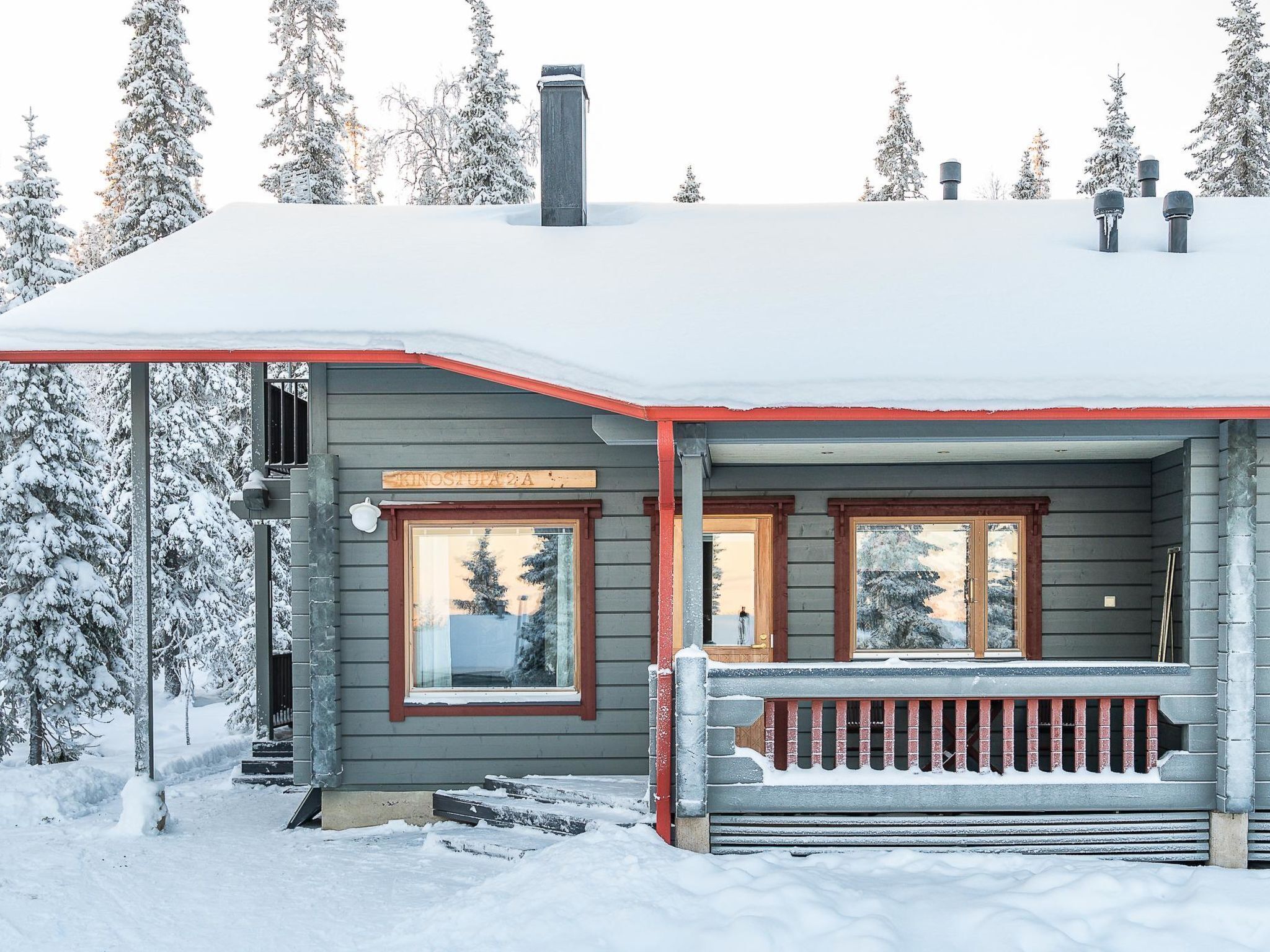 A wooden cabin with a covered porch, a chimney, and a sign above the entrance.