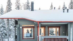 A wooden cabin with a covered porch, a chimney, and a sign above the entrance.
