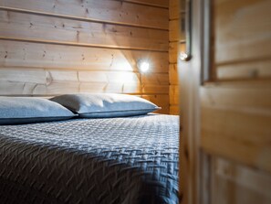A wooden interior with a bed, pillows, and a window.