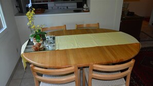 A dining area with a round wooden table, four chairs, a vase with yellow flowers, and a kitchen in the background. - Hübeli (Arm) by Interhome (Zweisimmen)