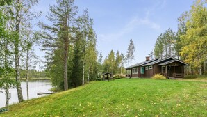 Mökki, jossa on nurmikkoon kasvava piha ja näkymä järvelle.