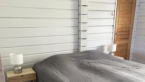 Makuuhuoneessa on yksi sänky, yöpöytä, jossa on lamppu, ja puinen ovi.