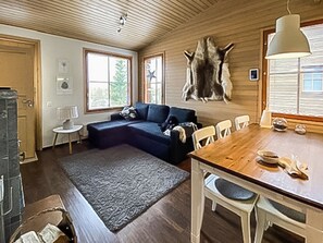A cozy cabin interior with a wooden dining table, a blue sofa, and a large fur rug.