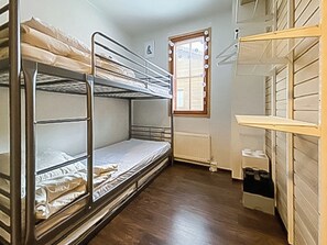 Een slaapkamer met een stapelbed, raam en radiator.