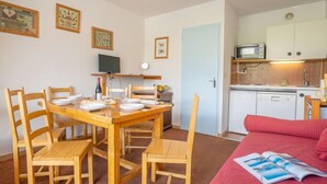 A compact living space with a dining area, kitchenette, and a bed. - Lac du Lou 506 by Interhome (Val Thorens)