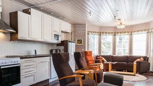 Eine moderne Küche mit weißen Schränken und einem Essbereich mit braunem Sofa und Stühlen.