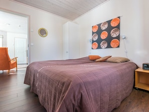 Une chambre à coucher avec un grand lit, une chaise, un miroir fixé au mur et un tableau.