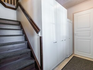 Un escalier avec des marches en bois et une rampe, menant à une porte blanche dotée d’une poignée.