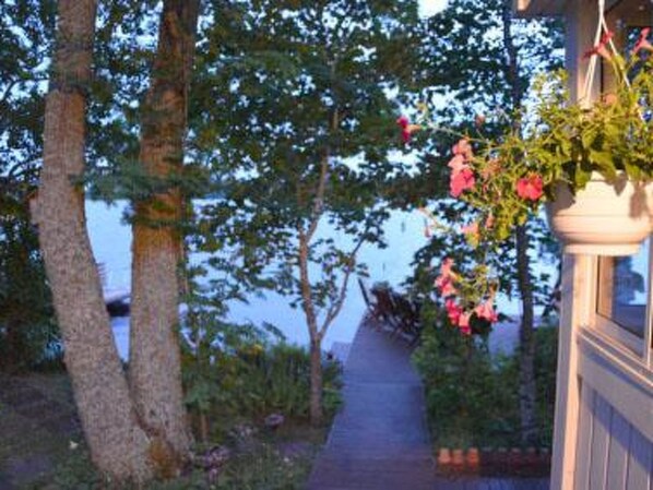 A pathway leading to a building with a hanging flower pot.