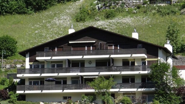 Una cabaña de varios pisos con balcones, ubicada en un entorno verde y exuberante.