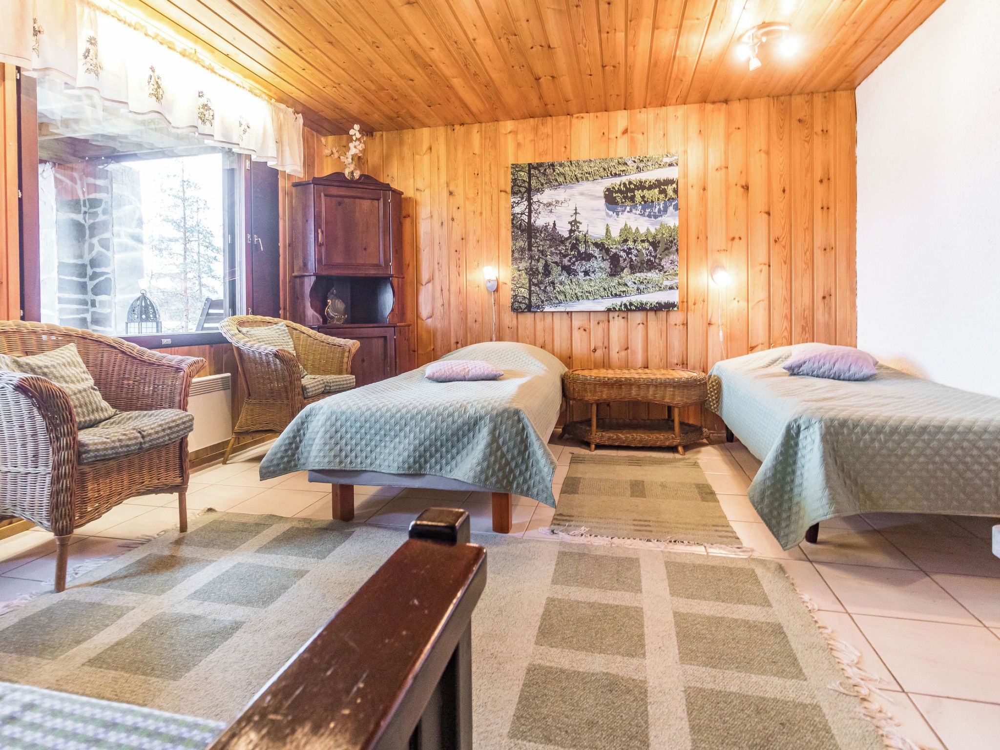 Ein gemütliches Zimmer mit zwei Betten, Korbmöbeln, einem Holzschrank und einem Bild an der Wand.