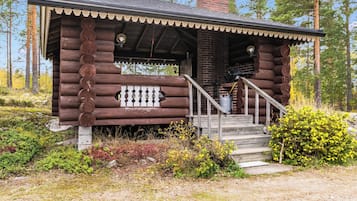 Eine Blockhütte mit Veranda, Schornstein und einer kleinen Treppe zum Eingang.