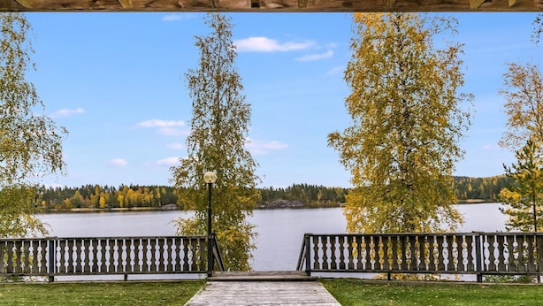 Une terrasse en bois qui mène à un lac, offrant une vue dégagée sur l’eau et les arbres environnants.