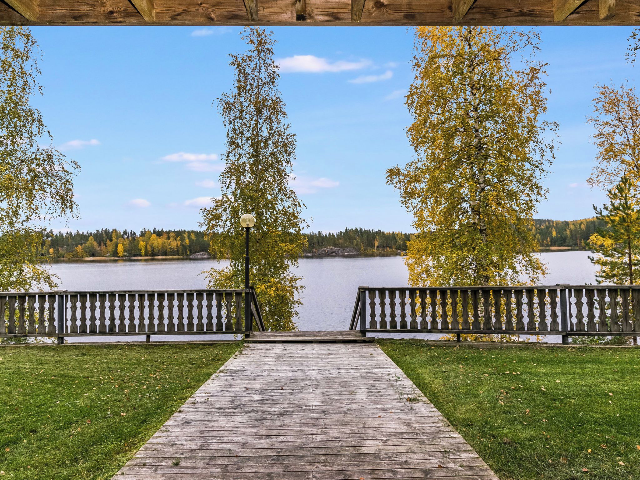 Une terrasse en bois qui mène à un lac, avec des bancs de chaque côté.