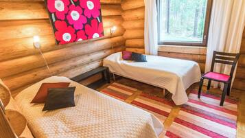 Une chambre de style rustique avec deux lits, une chaise, une fenêtre avec des rideaux et un mur orné d’un motif floral.