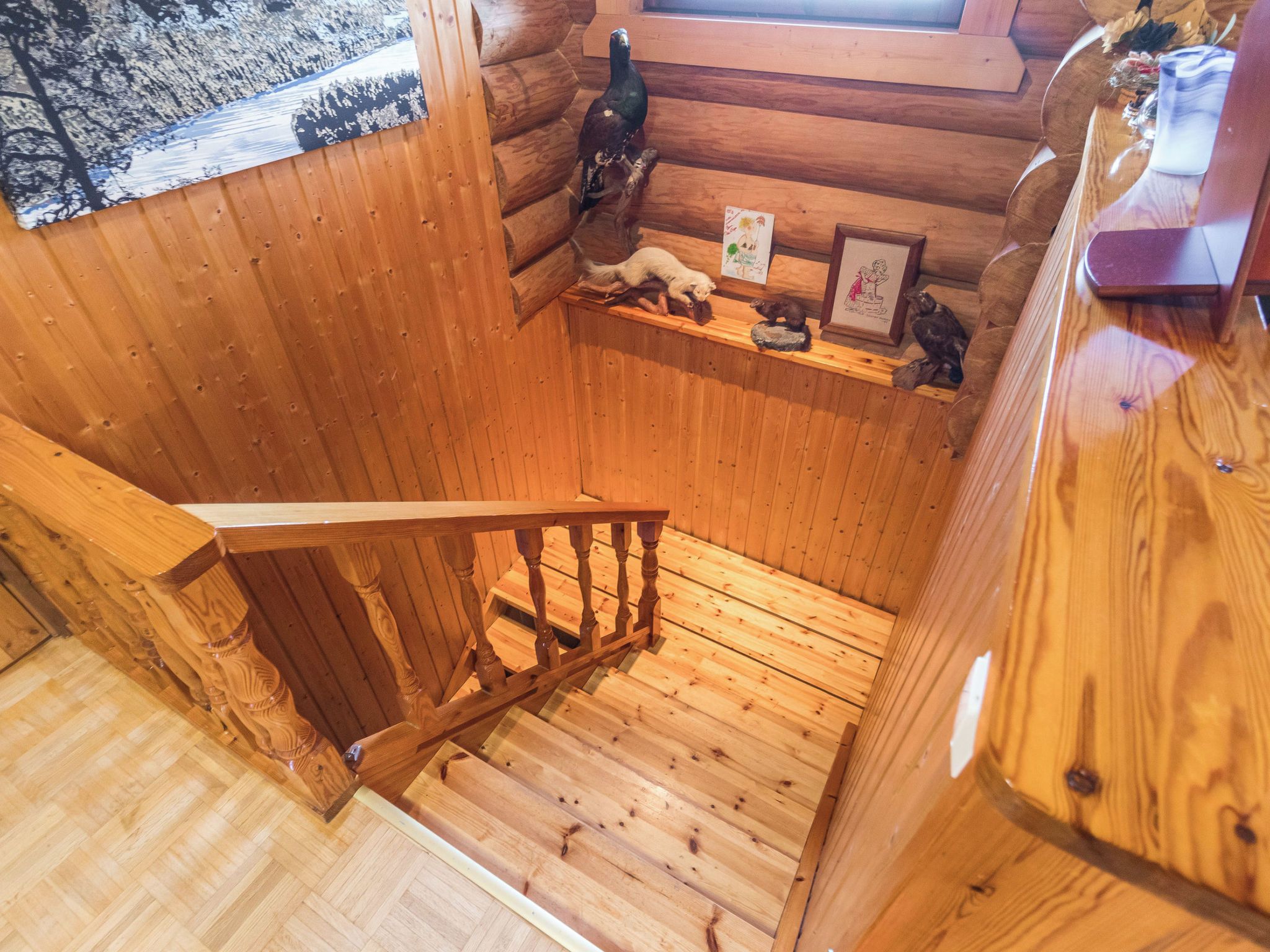 A wooden cabin interior with a wooden staircase, a wooden bench, and a small shelf with decorative items.