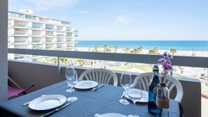 A balcony table set for dining with a view of the ocean and a hotel building. - Ipanema Sud by Interhome (Canet-Plage)