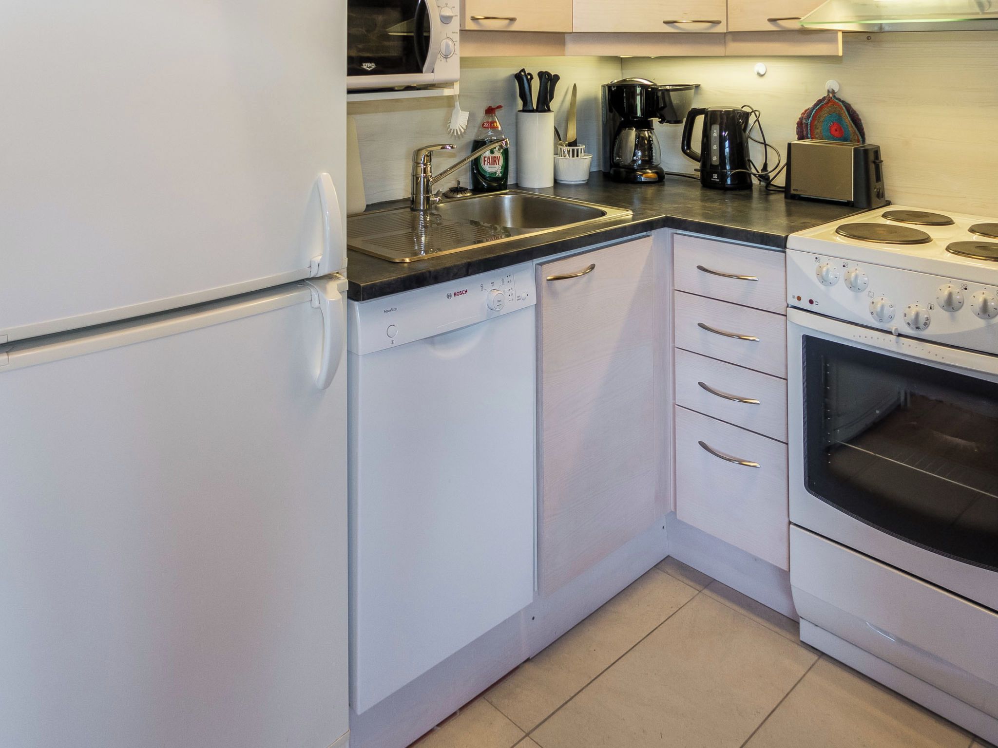 A kitchen with a Bosch dishwasher, a stove with four burners, and a coffee maker.