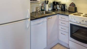 A kitchen with a Bosch dishwasher, a stove with four burners, and a coffee maker.
