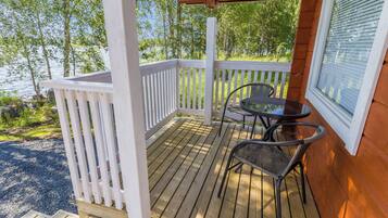 A wooden deck with a white railing, two chairs, and a table.