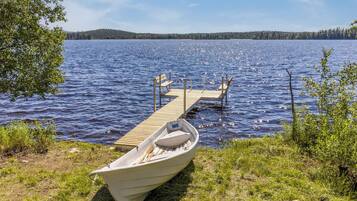 A boat docked at a pier with a clear view of a lake and distant hills.