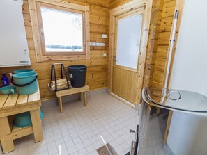 Una cabaña de madera compacta con kitchenette, una ventana y una pequeña mesa con un cubo de basura.