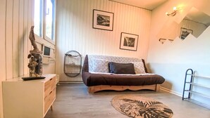 Un dormitorio con cama, mesita de noche, cómoda, ventana y estante fijado a la pared.