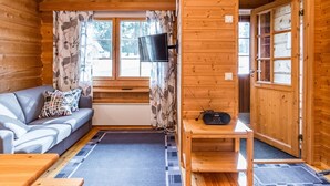 A cozy cabin interior with a sofa, a small table, and a television mounted on the wall. - Rukansyli 1 by Interhome (Kuusamo)