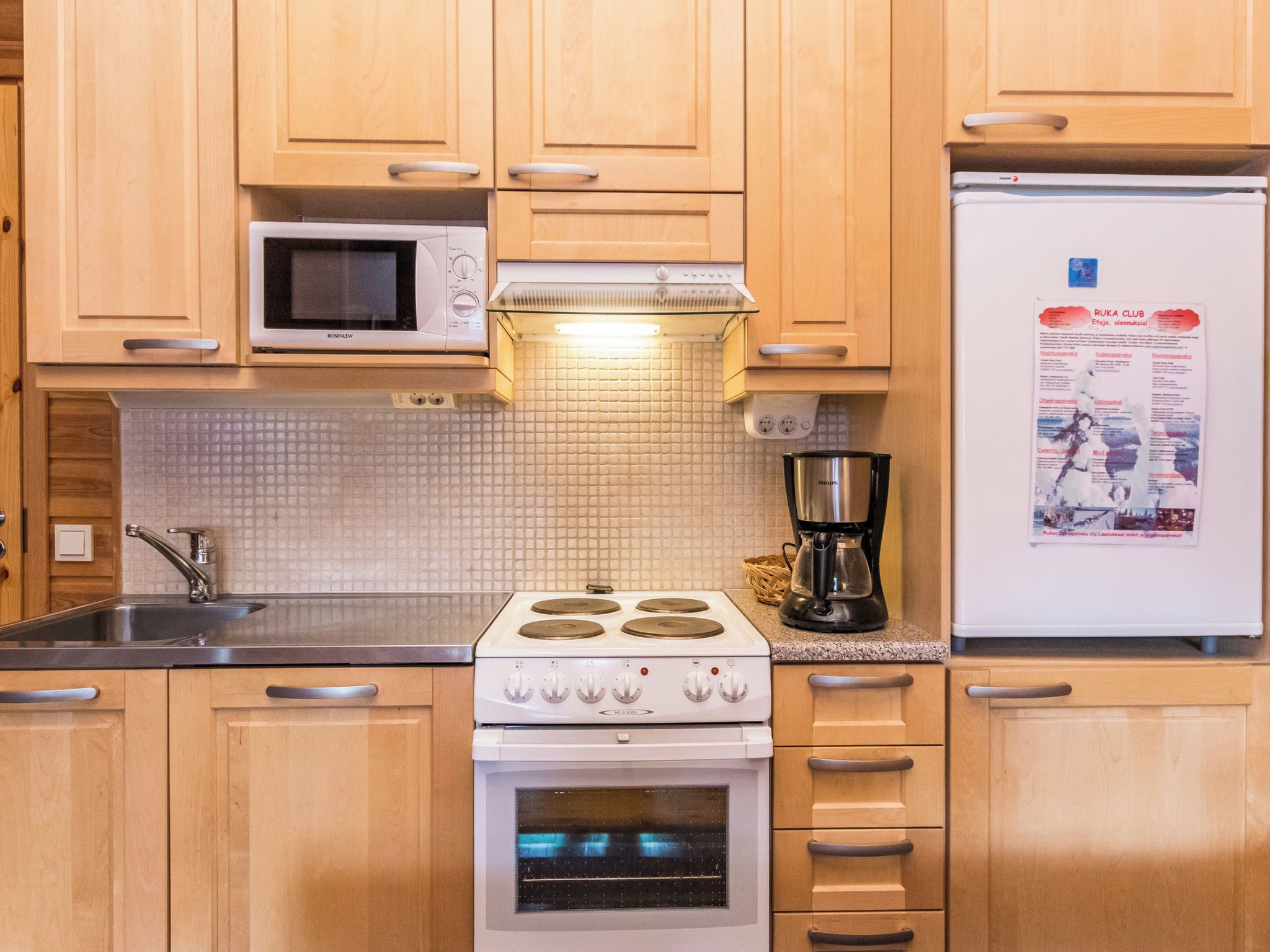 Une cuisine avec des meubles de rangement en bois, un four à micro-ondes, une cuisinière, un évier et un réfrigérateur.