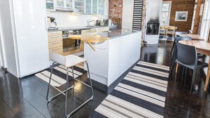 A modern kitchen with white cabinets, a wooden island, and a striped rug. - Säikkäranta by Interhome (Oulunsalo)