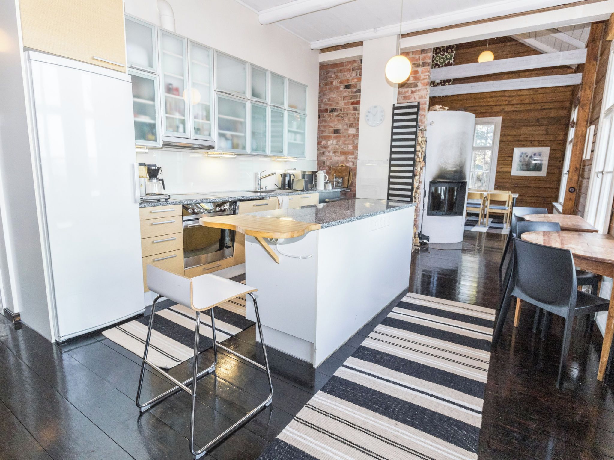 Una cocina moderna con armarios blancos, una isla central y una pared decorada con ladrillos.