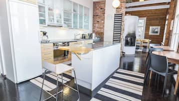 Una cocina moderna con armarios blancos, una isla central y una pared decorada con ladrillos.