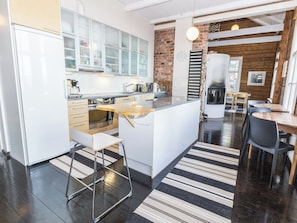 A modern kitchen with white cabinetry, a central island, and a brick accent wall.