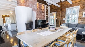 A spacious living area with a large wooden dining table, comfortable seating, a fireplace, and a cozy seating area with a couch. - Säikkäranta by Interhome (Oulunsalo)