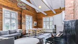 A cozy living room with a piano, a sofa, a dining table with chairs, and large windows. - Säikkäranta by Interhome (Oulunsalo)