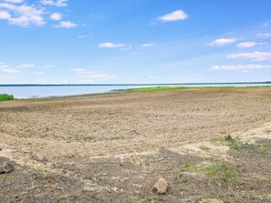 Ein weiter, offener Strand mit blauem Himmel und ruhigem Wasser im Hintergrund.