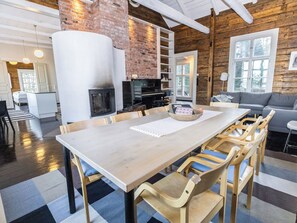 A spacious living area with a large wooden table, comfortable seating, a fireplace, and a television.