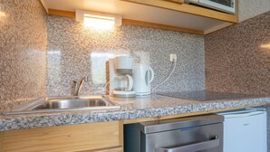 Una cocina con encimeras de granito, cafetera, lavavajillas y armarios de madera.