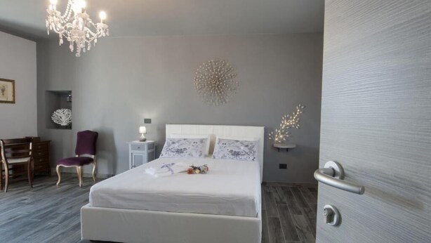 A modern bedroom with a large bed, a chandelier, a desk, and a chair. - Il Bosco Delle Torte (Castellinaldo)
