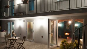 A modern two-story building with a balcony, a dining area with a table and chairs, and a visible fireplace in the interior. - Il Bosco Delle Torte (Castellinaldo)