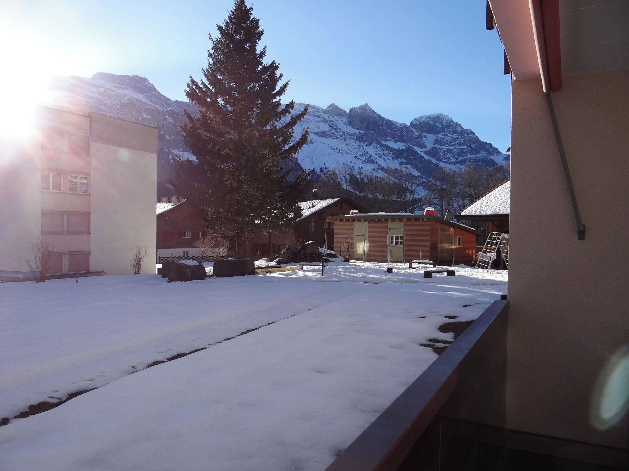 Paesaggio innevato con edifici e montagne sullo sfondo.