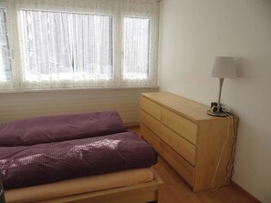 Une chambre à coucher avec un lit, une commode et une lampe.