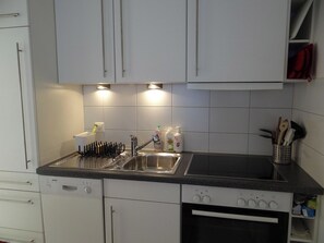 A kitchen with white cabinets, a Bosch dishwasher, a sink with a dish rack, and a stove. - Neuschwändi 66 Appartement/Fewo 4-Bettwohnung by Interhome (Engelberg)