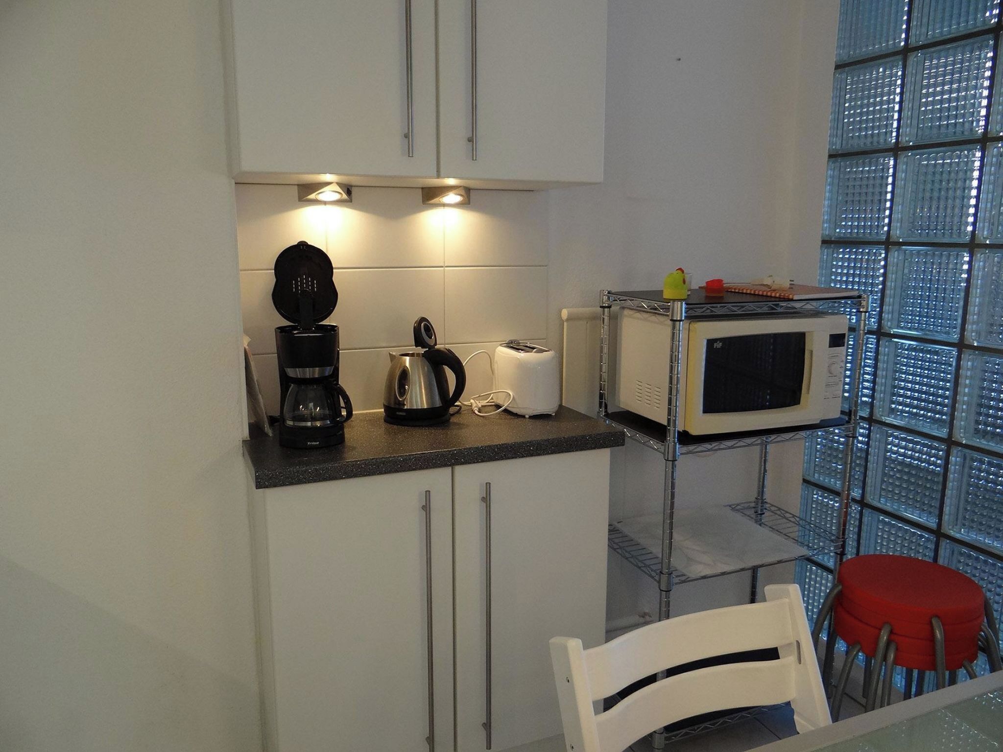 A compact kitchen with a coffee maker, toaster, and microwave on a countertop.