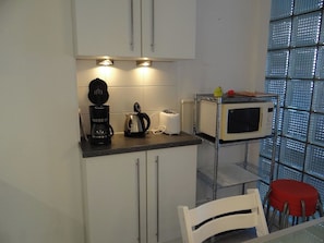 A compact kitchen with a coffee maker, toaster, and microwave on a countertop.