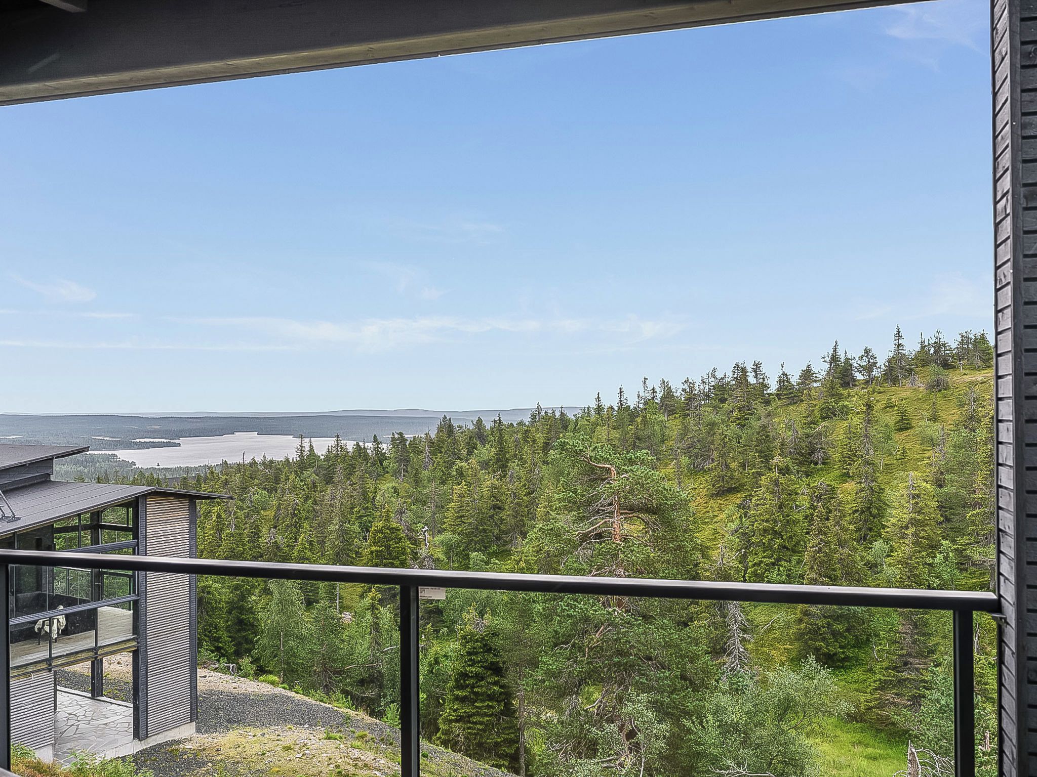 Un bâtiment moderne doté d’un balcon donnant sur un paysage boisé et un plan d’eau.