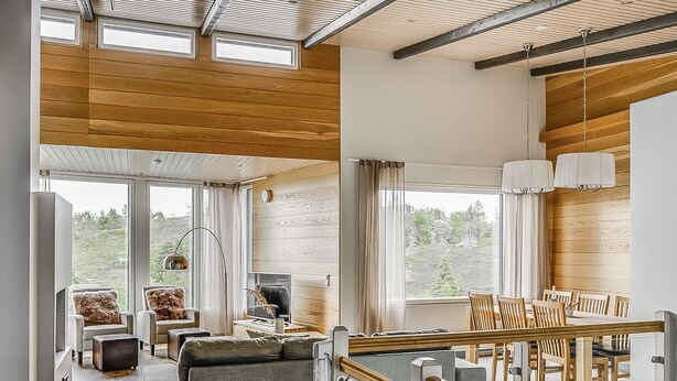 A spacious living area with a sofa, chairs, a dining table, and a TV.