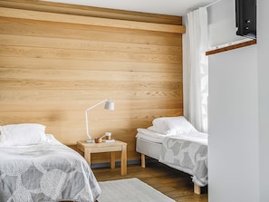 A bedroom with two single beds, a nightstand with a lamp, and a wooden headboard.