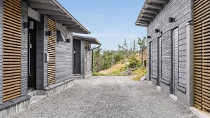 A modern building with a gravel driveway and wooden shutters on the windows.